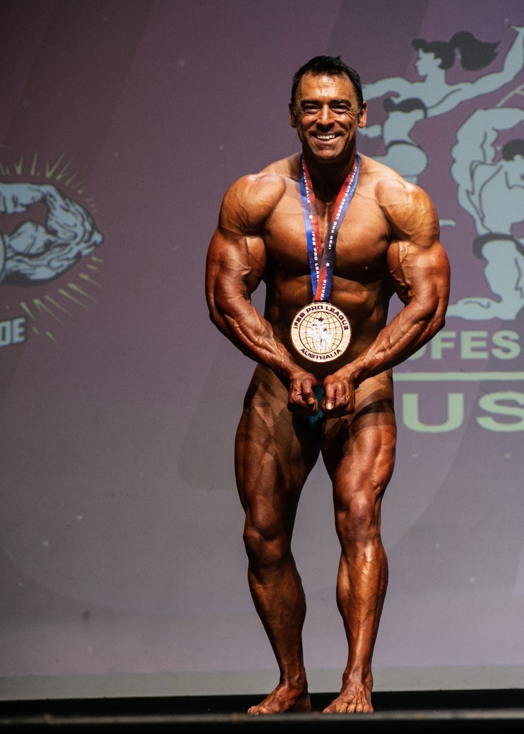 Competitive bodybuilder on stage wearing a medal